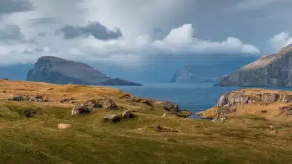 Dramatische Felsklippen und Fjord in nebeligem Licht mit einsamen Wanderer auf Bergkamm