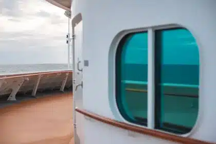 Passagiere auf dem Deck eines modernen Kreuzfahrtschiffs blicken aufs Meer