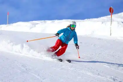 Skifahrer auf einer Pulverschneepiste vor schneebedeckten Bergketten