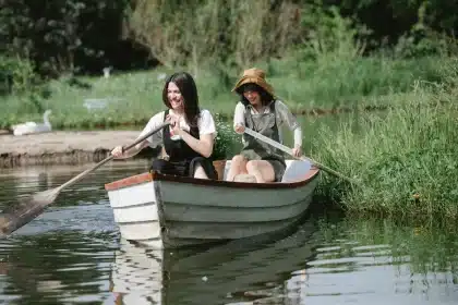 Ältere Frauen lachen zusammen auf einem Steg am See, umgeben von Natur und Booten.