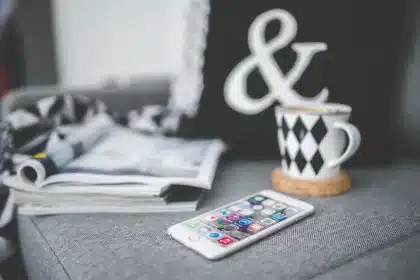 Hände halten Tablet mit digitalen Magazinen, Papierstapel im Hintergrund