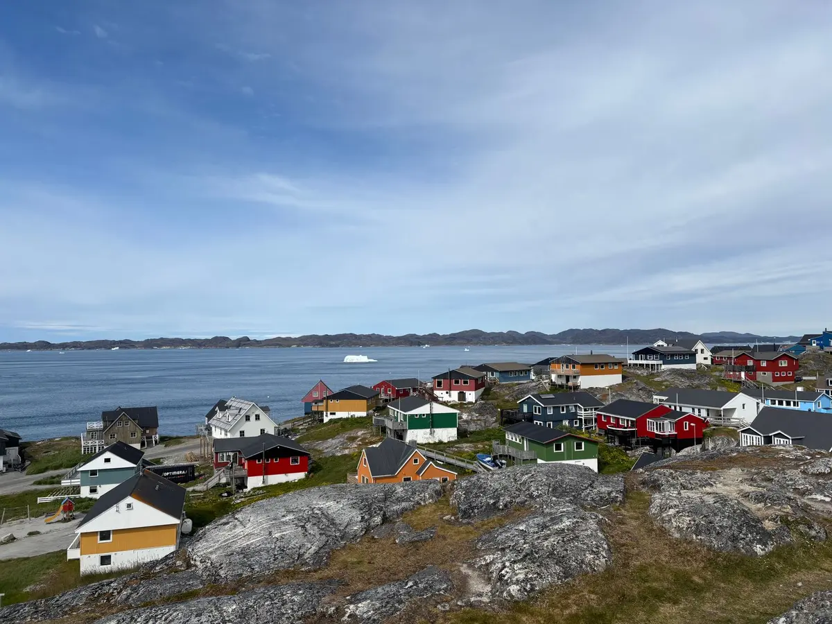 Kleine grönländische Küstensiedlung in einer Fjordlandschaft mit Natur