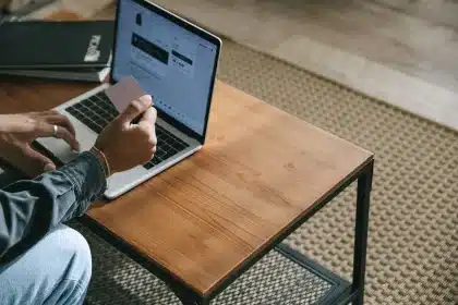 Hände scrollen durch eine E-Commerce-Website auf dem Laptop mit Produktlisten und Warenkorb-Symbolen