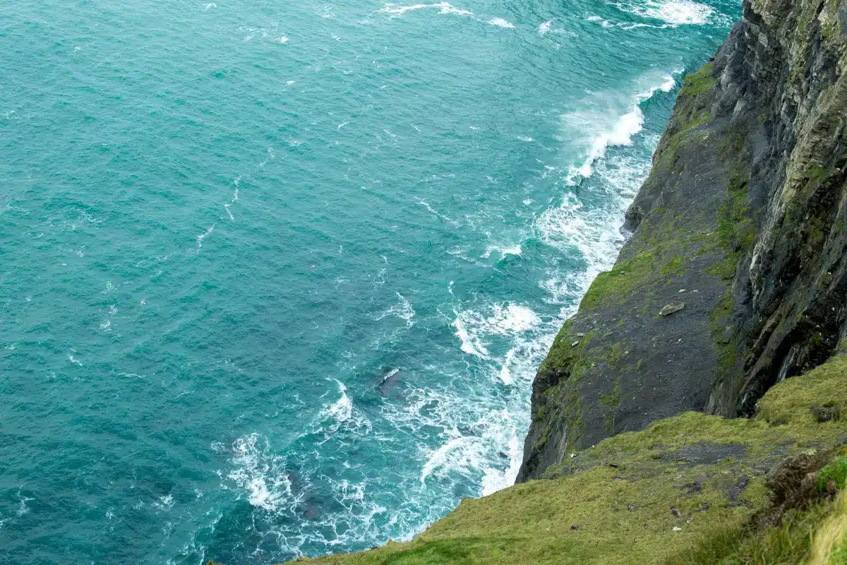 Dramatische Felsklippen an der irischen Atlantikküste mit Wellen und nebligem Himmel