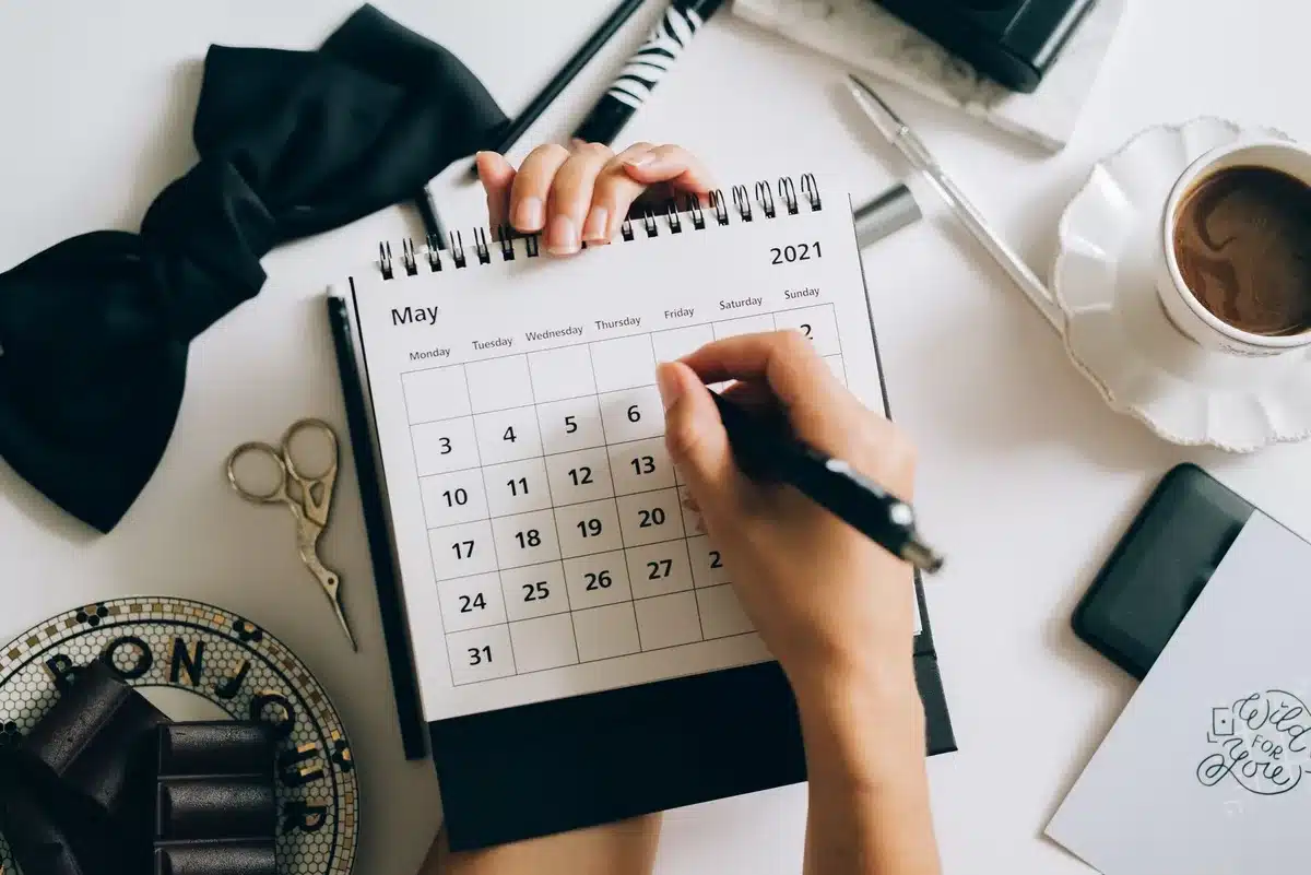 Frau plant ihre Reise mit Kalender und Laptop