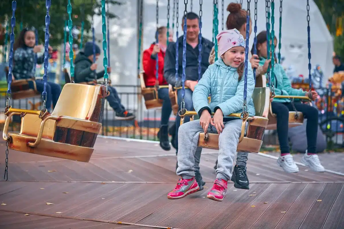 Eltern und Kinder unterschiedlichen Alters genießen gemeinsam eine Fahrgeschäfte im Park