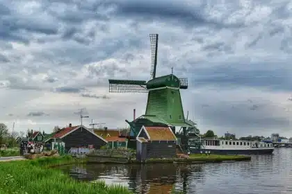Niederländischer Kanal mit Fahrrädern und historischen Häuserfassaden, Windmühle am Horizont