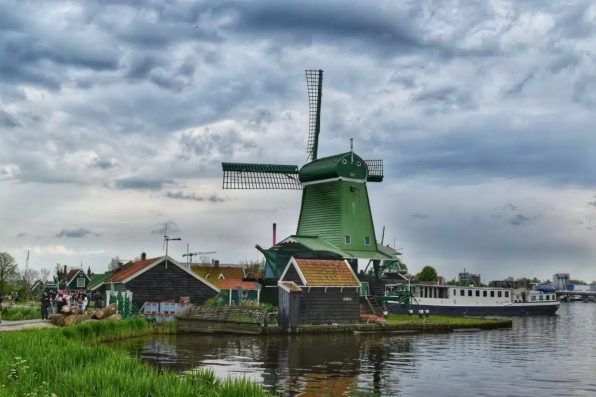 Niederländischer Kanal mit Fahrrädern und historischen Häuserfassaden, Windmühle am Horizont