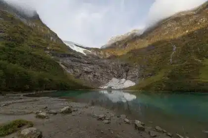 Steile Felswände eines norwegischen Fjords mit Wasser und entfernten Bergen
