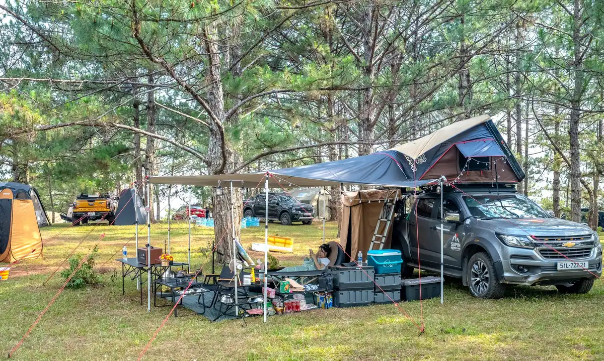 Tragbare Klimaanlage mit Solarpanel auf einem Campingtisch neben einem Zelt