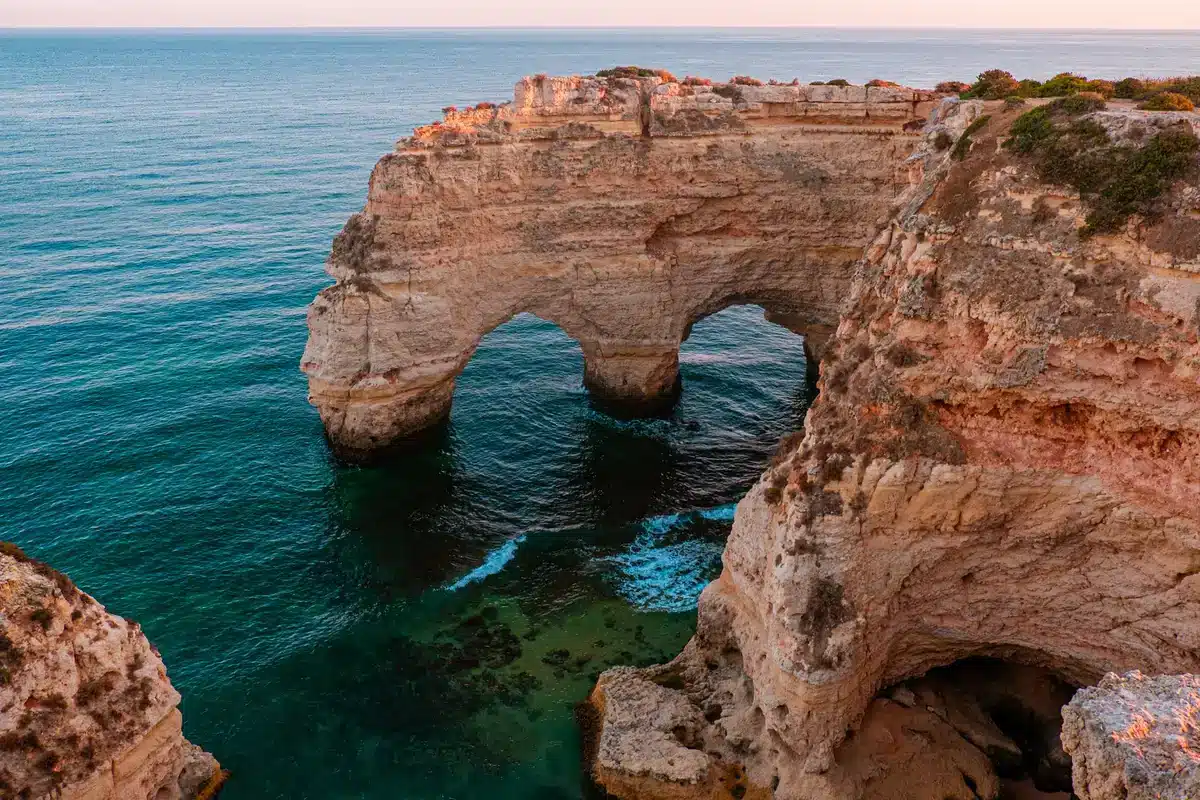 Steile Felsformationen an der Algarve mit golden leuchtender Küstenlinie