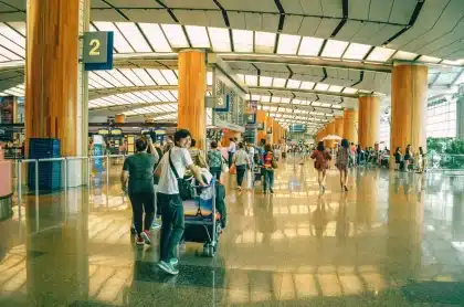 Reisende in einem Flughafenterminal während einer Flugstörung, mit Gepäck und Abfluganzeigetafeln
