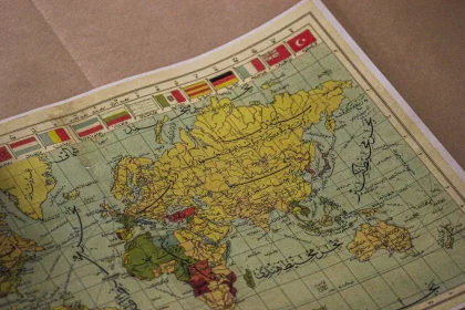 Eine Hand schreibt einen neuen Ortsnamen auf eine alte Weltkarte oder einen Globus.