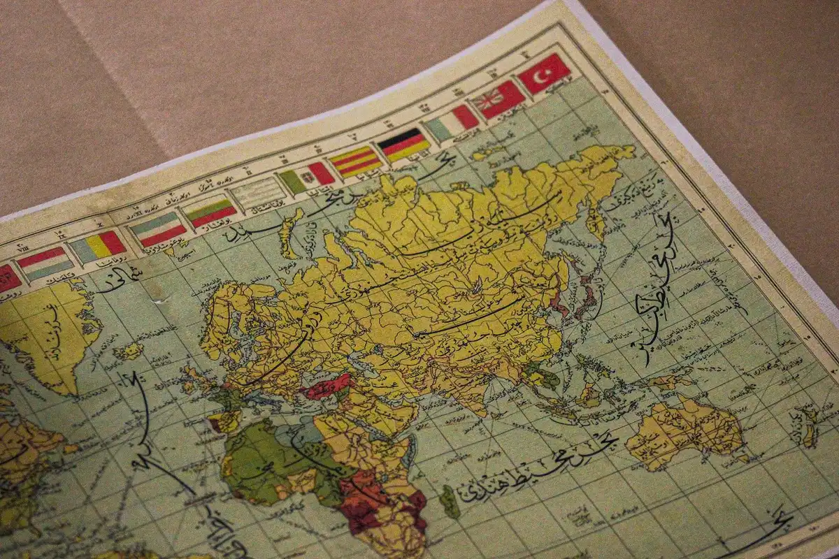 Eine Hand schreibt einen neuen Ortsnamen auf eine alte Weltkarte oder einen Globus.