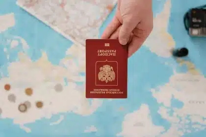 Reisender füllt digitales Einreiseformular am Laptop aus und hält seinen Reisepass bereit.