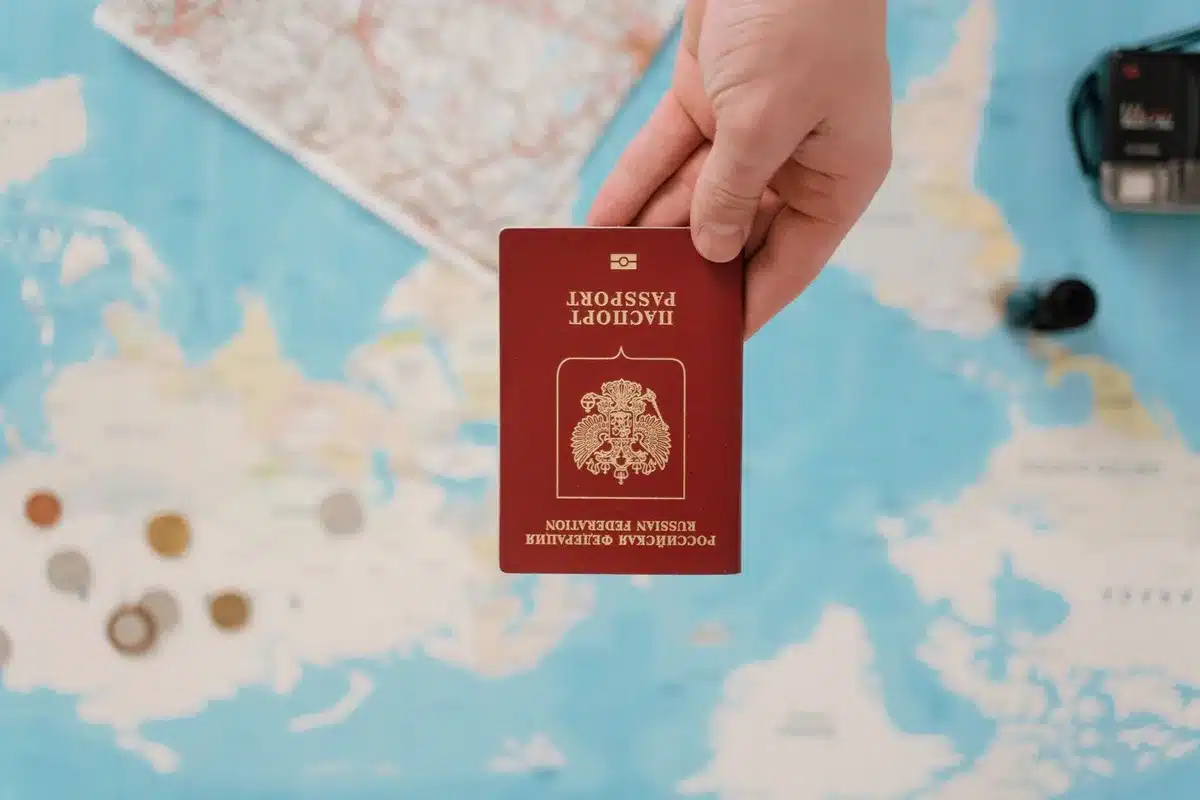Reisender füllt digitales Einreiseformular am Laptop aus und hält seinen Reisepass bereit.