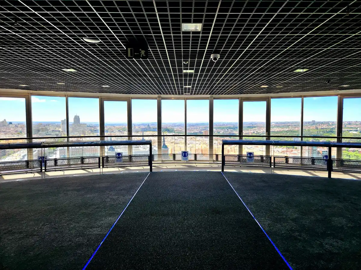 Besucherin steht auf einer gl&auml;sernen Plattform mit Blick nach unten auf die Stadt