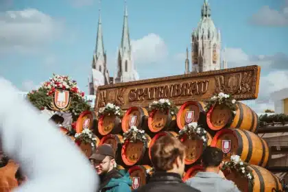 Anonyme Besucher in traditioneller Kleidung stoßen mit Bierkrügen in einem festlich geschmückten Zelt an