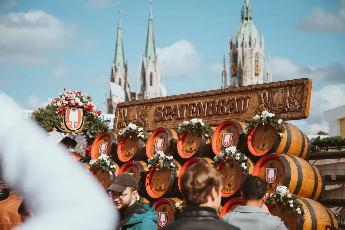 Anonyme Besucher in traditioneller Kleidung stoßen mit Bierkrügen in einem festlich geschmückten Zelt an