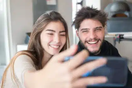 Hand hält Smartphone mit romantischem Social-Media-Post in warmem Licht