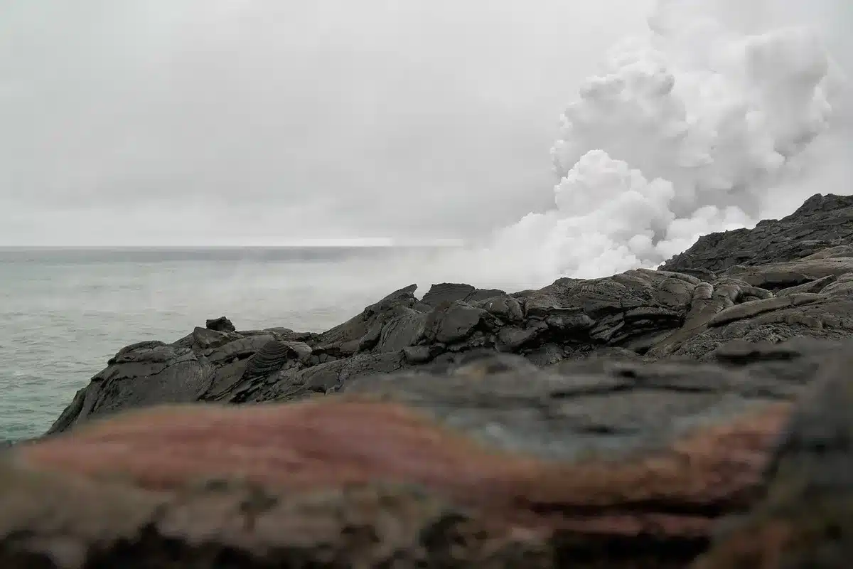 Vulkan st&ouml;&szlig;t dunkle Asche- und Rauchs&auml;ule &uuml;ber Meer und Inseln aus