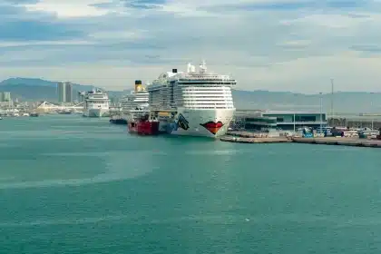 Passagiere an der Reling eines Kreuzfahrtschiffes blicken auf das Meer