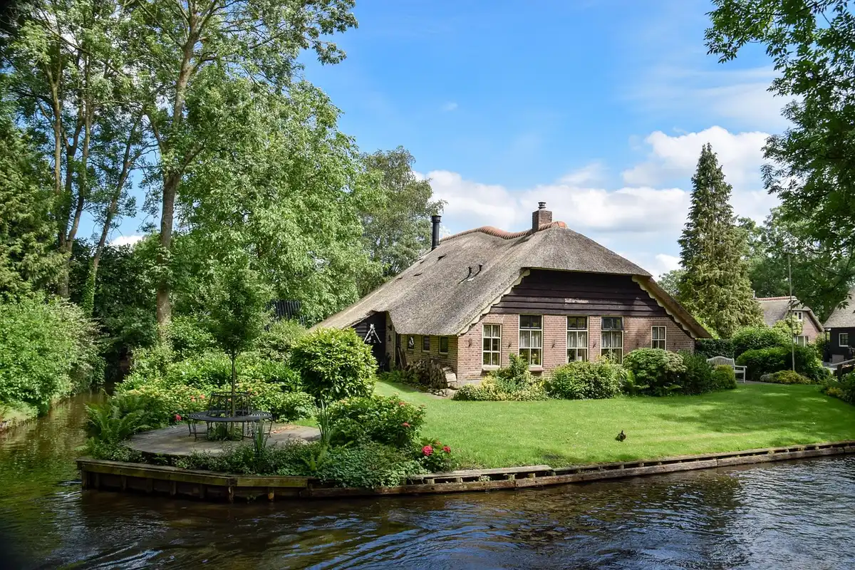 Traditionelle H&auml;user entlang von Kan&auml;len in Giethoorn mit Booten im Wasser