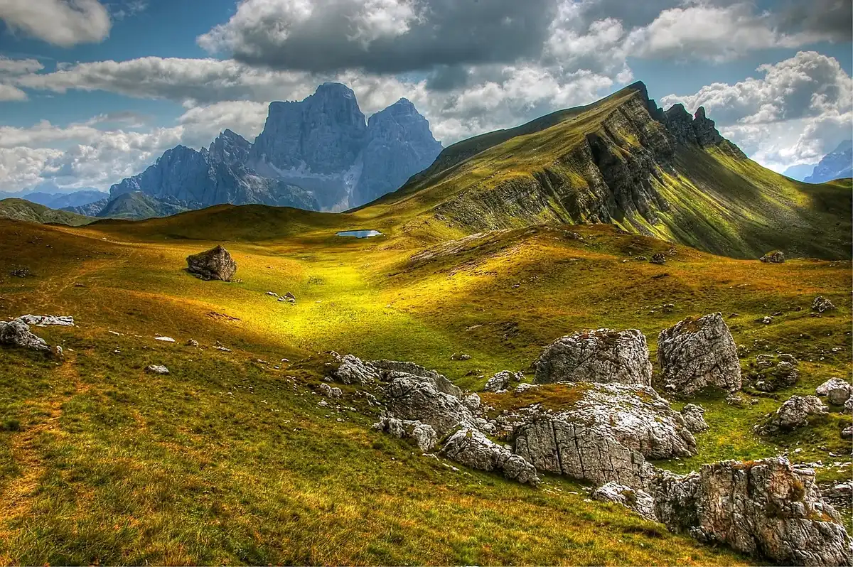 Stiller Bergsee mit steilen Felsw&auml;nden und gr&uuml;nen Almwiesen in den Alpen