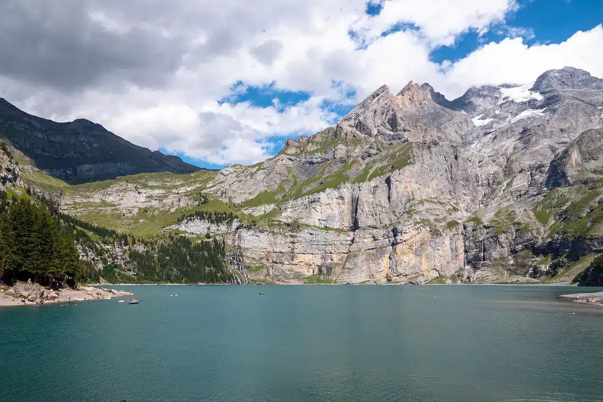Alpental mit türkisem Bergsee, schneebedeckten Gipfeln und traditionellen Chalets in malerischer Landschaft