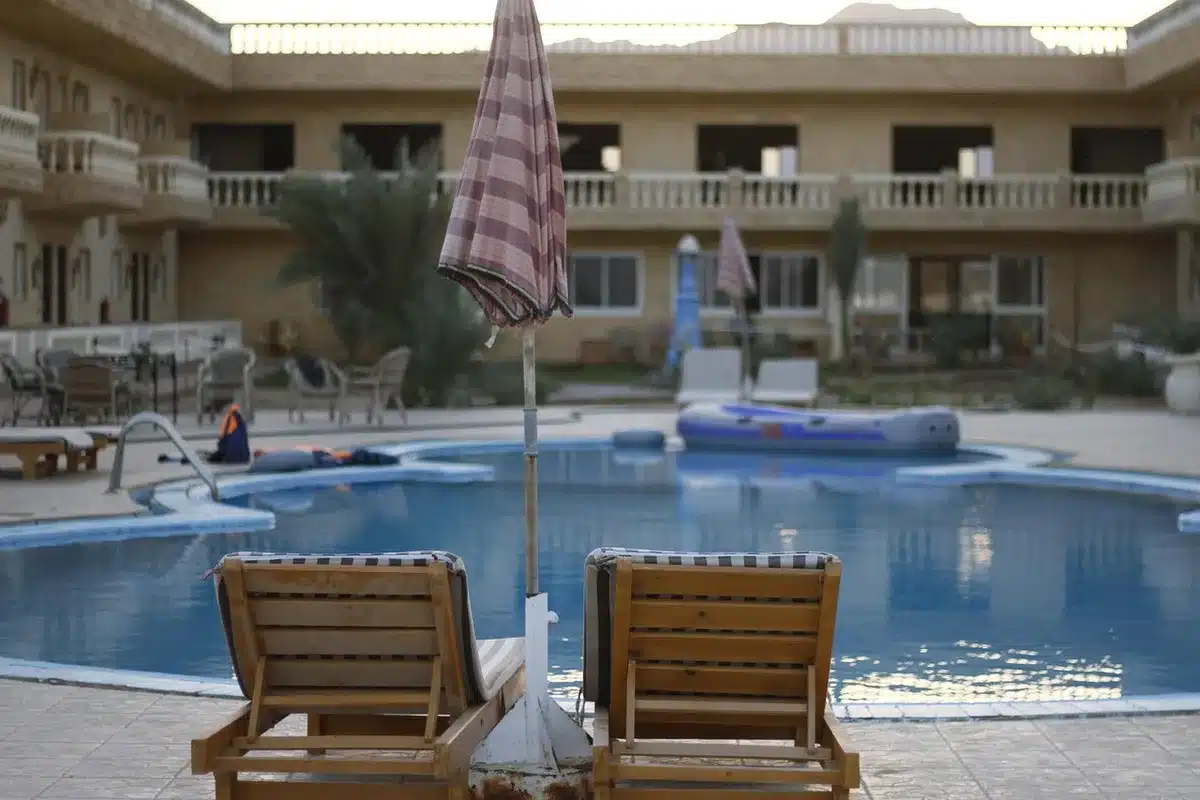 Hotelpool mit Schild zu Reservierungsregeln und leeren Liegen