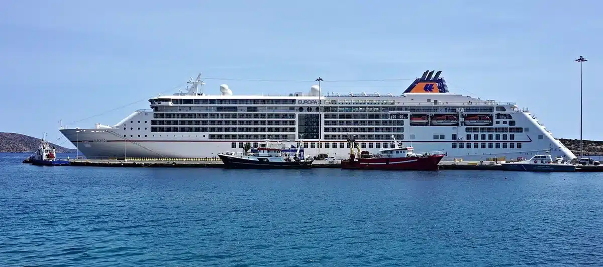 Karte und Reiseroute auf einem Tisch mit einem Modellschiff als Symbol für Themenkreuzfahrt
