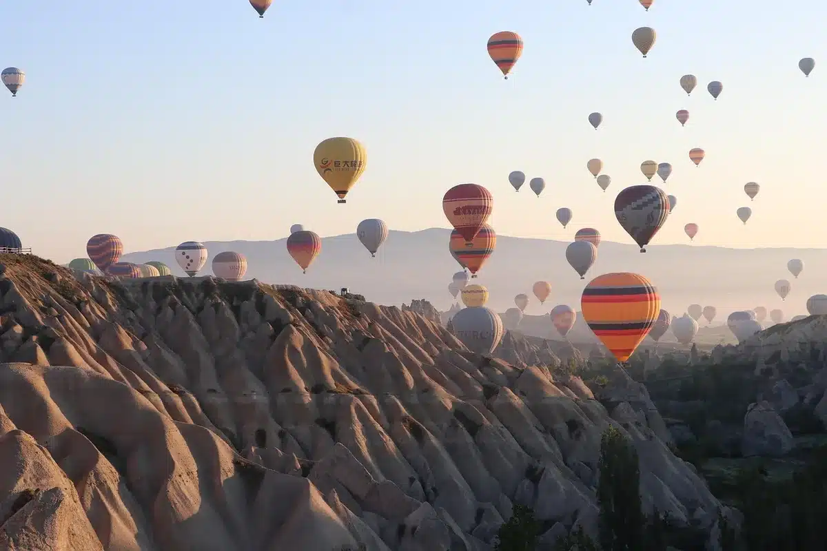 Hei&szlig;luftballone schweben &uuml;ber die Felst&uuml;rme Kappadokiens bei Sonnenaufgang