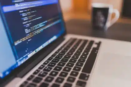 Junge Frau arbeitet konzentriert an ihrem Schreibtisch im Redaktionsbüro mit Computer und Notizen.