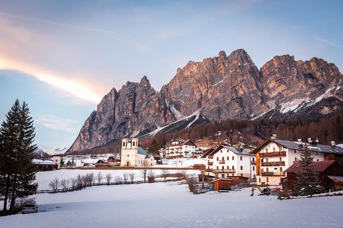 Winterliche Straße mit Schnee, parkenden Autos und verschneiter Landschaft