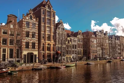 Fahrräder an einem Amsterdamer Kanal, Blick auf eine Brücke und ein Elektroboot
