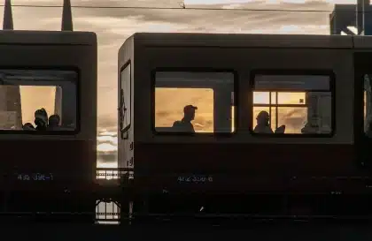 Anonyme Pendler auf einem Bahnsteig mit Flaschen und Bahnhofsuhr