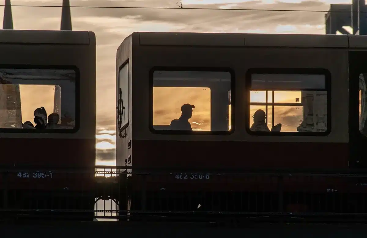 Anonyme Pendler auf einem Bahnsteig mit Flaschen und Bahnhofsuhr