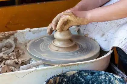 Hände füllen ein Holzgefäß mit Gemüse für Fermentation auf Tatami-Boden