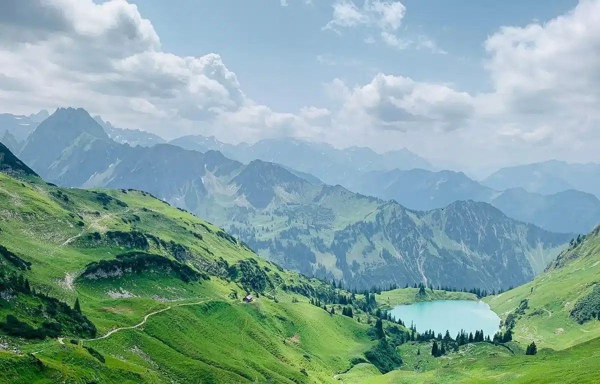 Wanderweg mit Blick auf einen Bergsee und bewaldete Ufer