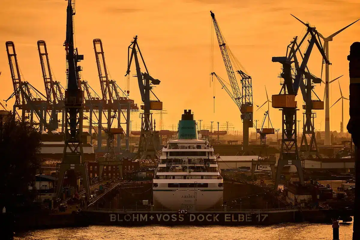 Silhouetten von Werftarbeitern neben einem Stahlblock und einer Münze im Dock