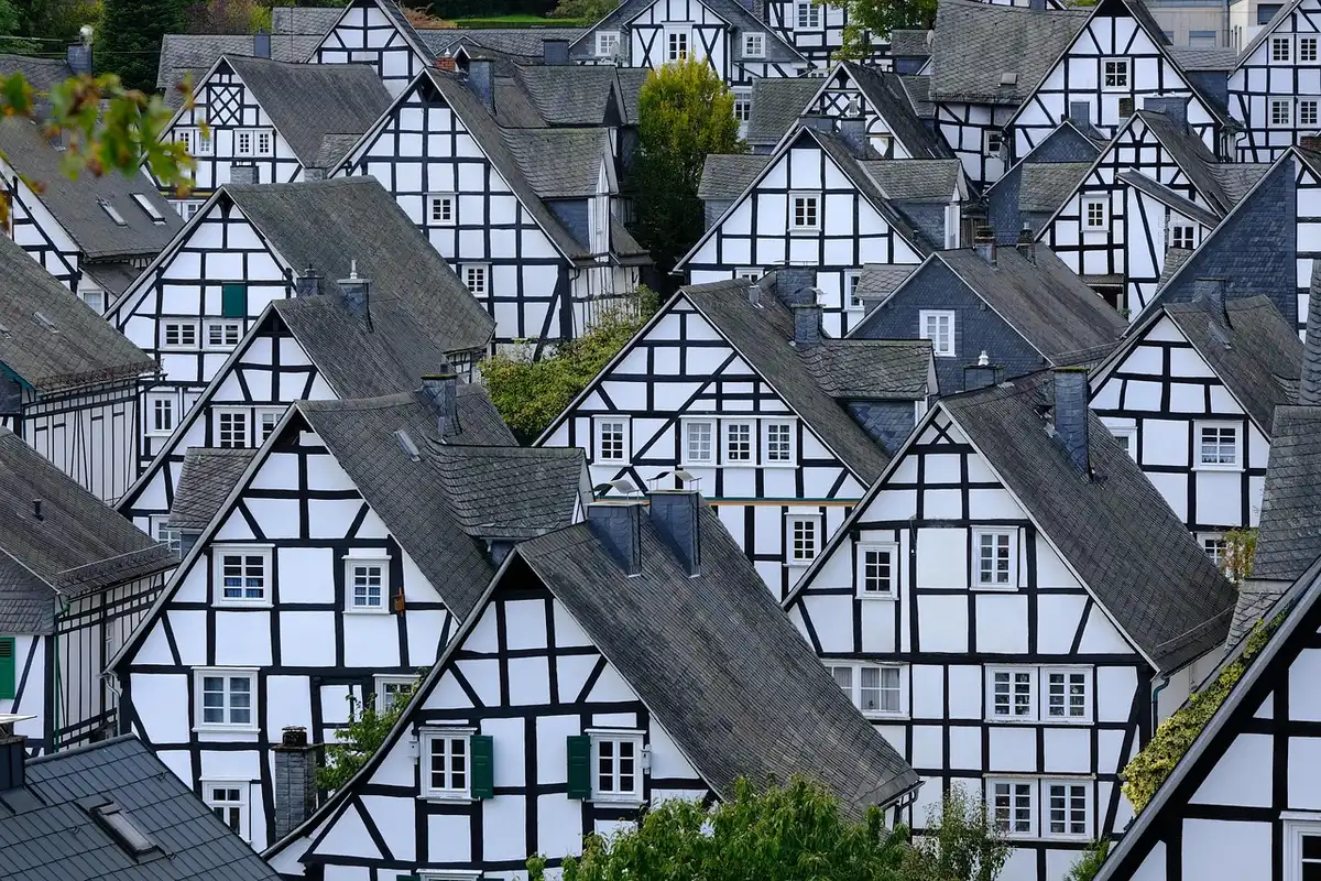 Anonyme Besucher zwischen Holzbuden und beleuchteten Fachwerkhäusern auf einem Weihnachtsmarkt
