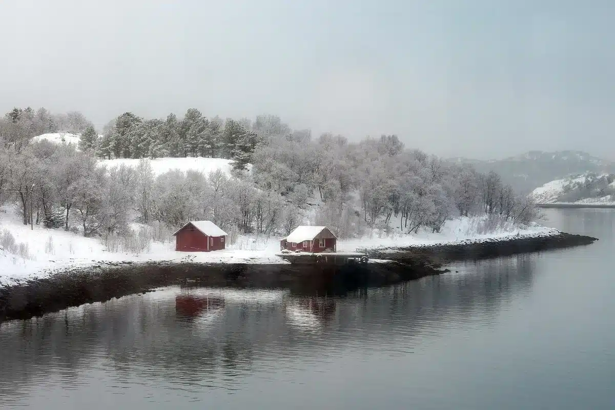 Ein anonymes Saunafloß aus Holz auf einem ruhigen Fjord im Winter