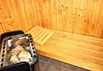 Holzsauna-Anhänger am windigen Strand mit Meerblick und Menschen in Handtüchern