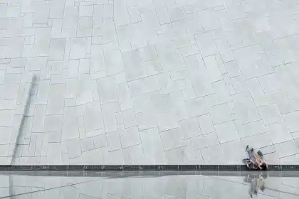 Abstrakte Beton-Skulptur in einer weiten Landschaft, silhouette einer entfernten Person