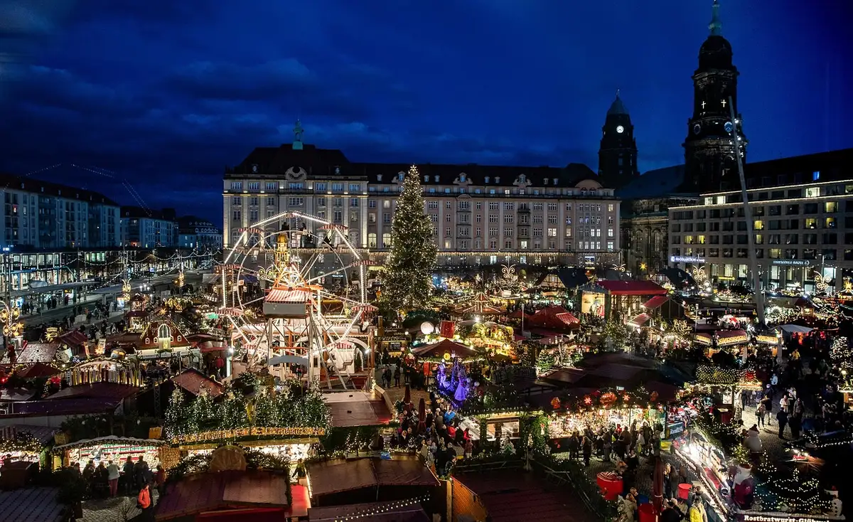 Beleuchtetes Schiff am Ufer mit weihnachtlichen Ständen auf dem Deck