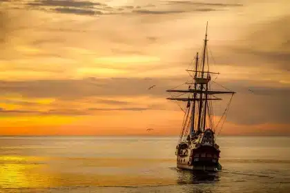 Modellschiff auf Fensterbank vor hellem Hafenblick, symbolisch für Besitz und Reise