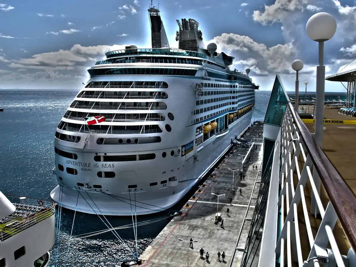 Reisende auf Kreuzdeck blicken auf im Hafen liegendes Schiff